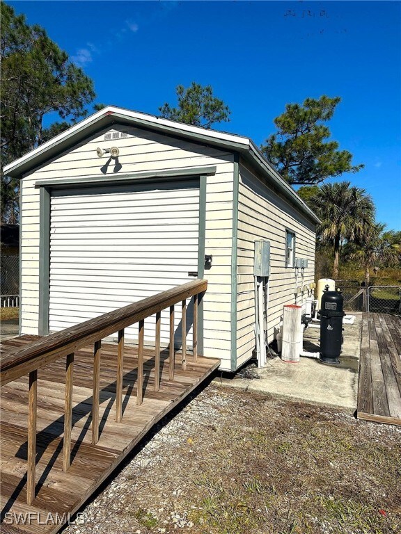 view of side of property with a garage, an outdoor structure, and a wooden deck