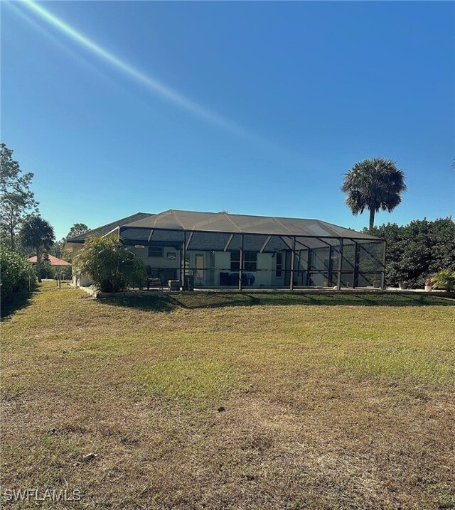 back of property with a yard and glass enclosure