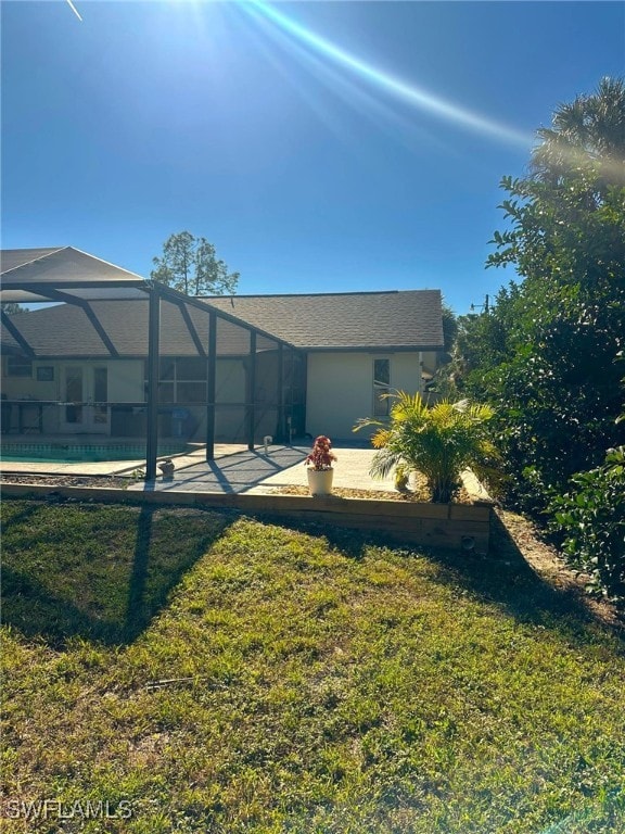 rear view of property with a swimming pool, a patio area, glass enclosure, and a lawn