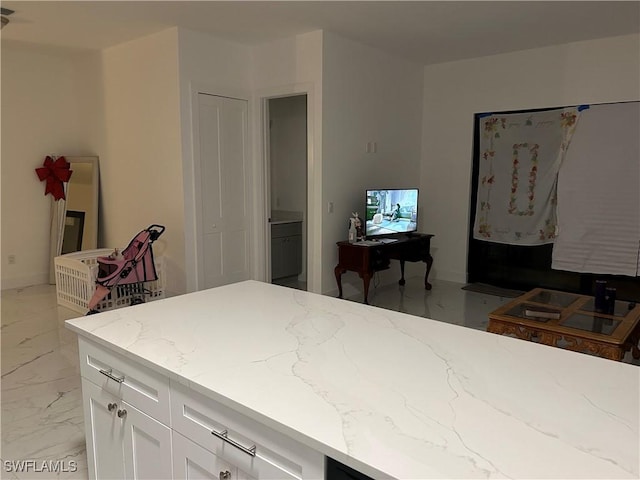 kitchen featuring light stone counters and white cabinets