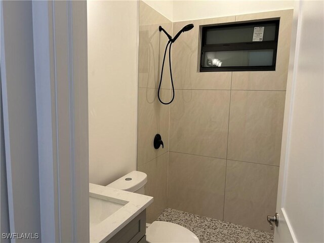 bathroom with vanity, tiled shower, and toilet