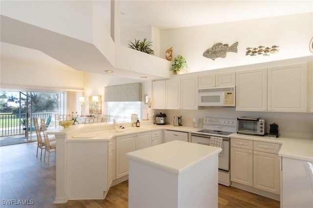 kitchen featuring white cabinetry, white appliances, a center island, and sink