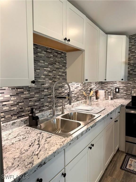 kitchen with white cabinets, sink, dark hardwood / wood-style floors, stainless steel electric range oven, and tasteful backsplash