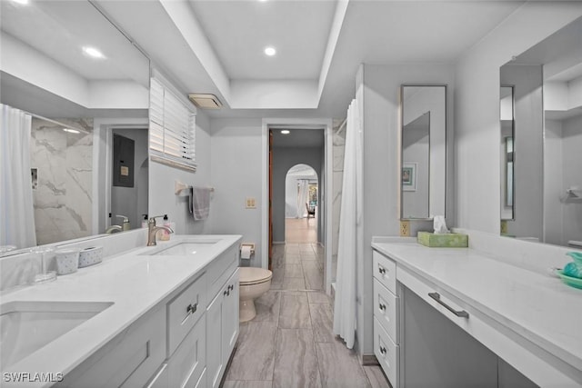 bathroom with a shower with curtain, vanity, a tray ceiling, and toilet