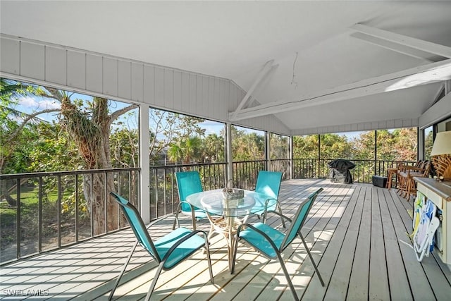 sunroom / solarium featuring vaulted ceiling with beams