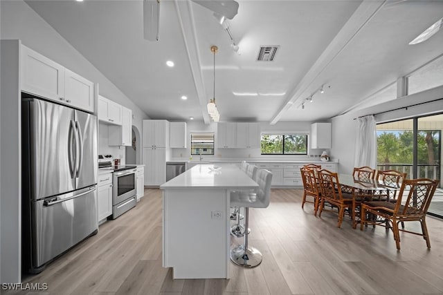 kitchen with vaulted ceiling with beams, a kitchen island, white cabinetry, and stainless steel appliances