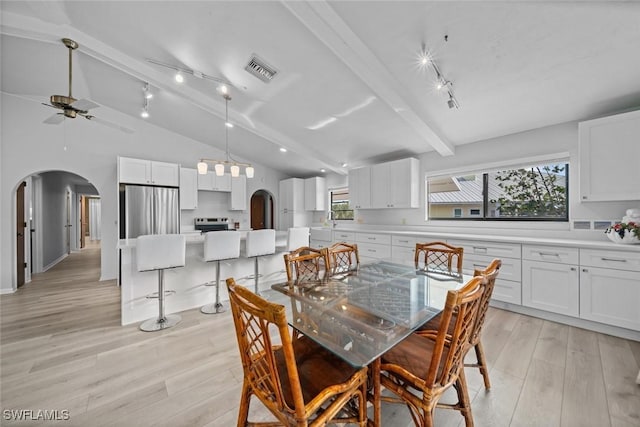 dining room featuring light wood-type flooring, vaulted ceiling with beams, rail lighting, and ceiling fan