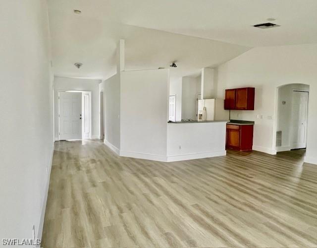 unfurnished living room with lofted ceiling and light wood-type flooring