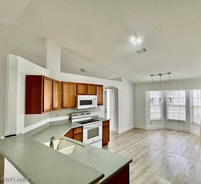 kitchen featuring kitchen peninsula, decorative light fixtures, sink, white appliances, and light hardwood / wood-style floors