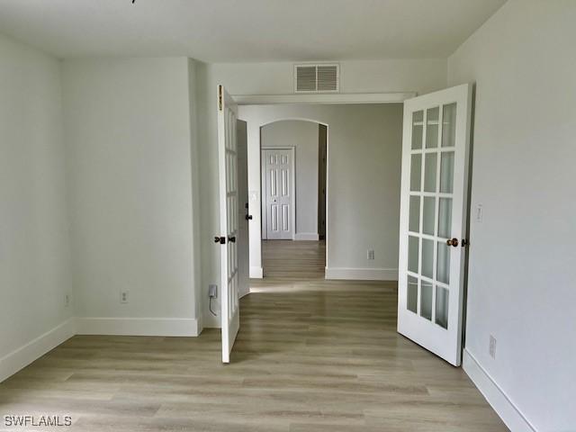 empty room with light hardwood / wood-style floors and french doors