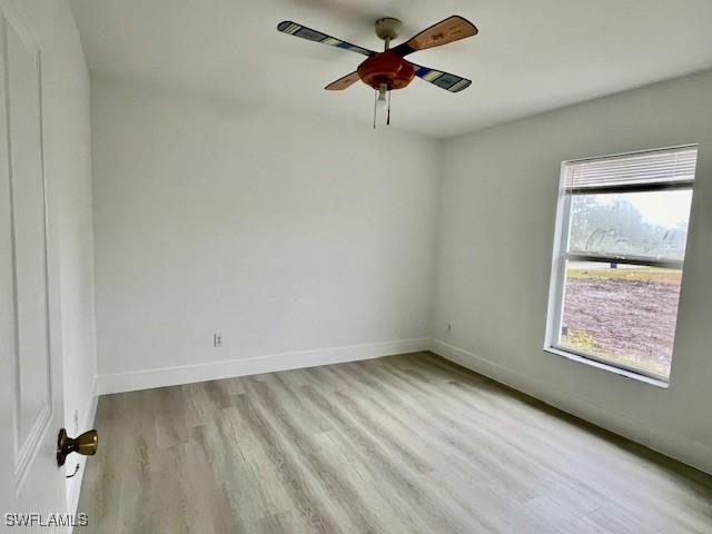 spare room with light wood-type flooring, ceiling fan, and a wealth of natural light