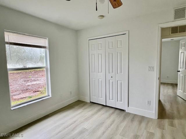 unfurnished bedroom with light hardwood / wood-style flooring, a closet, and ceiling fan