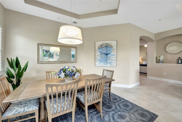 dining area with a raised ceiling and light tile patterned floors