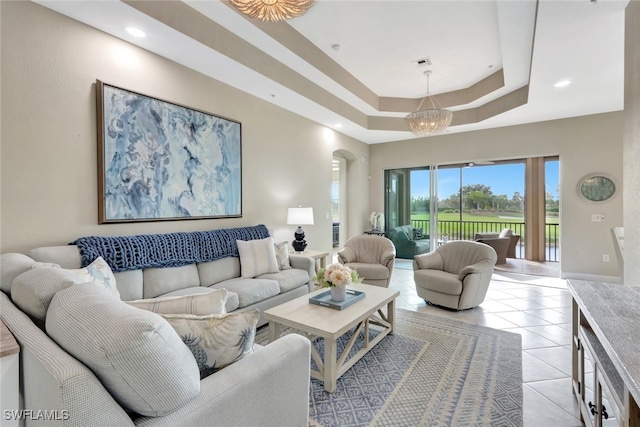 living room with light tile patterned floors, a notable chandelier, and a tray ceiling