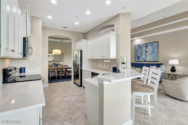 kitchen with backsplash, stainless steel appliances, white cabinetry, and sink