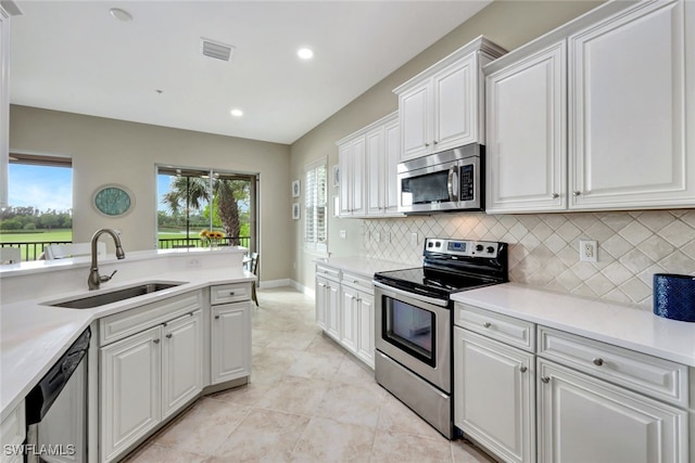 kitchen with backsplash, sink, light tile patterned floors, appliances with stainless steel finishes, and white cabinetry