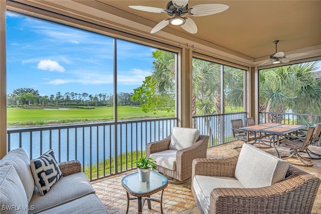 sunroom featuring ceiling fan and a water view