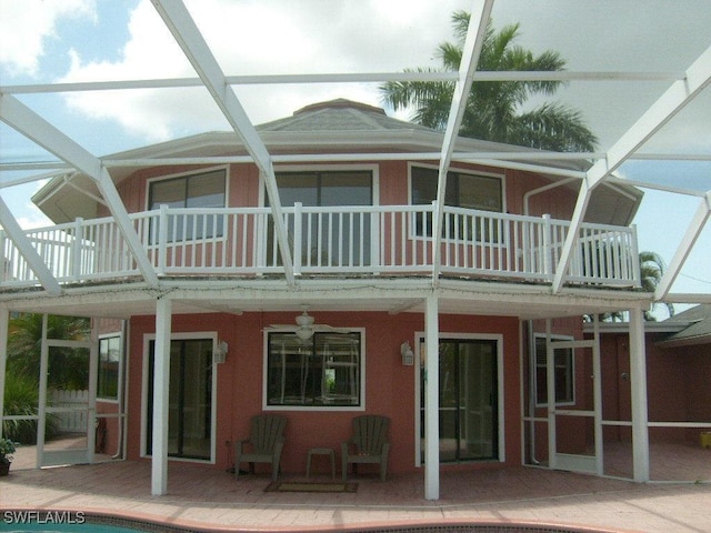 back of property with glass enclosure and ceiling fan