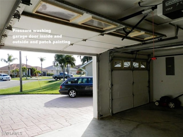 garage with a lawn, electric panel, and a garage door opener