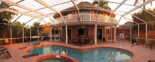 view of swimming pool featuring glass enclosure, a patio area, and an in ground hot tub