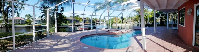 view of swimming pool with a lanai, a patio area, a water view, and a hot tub