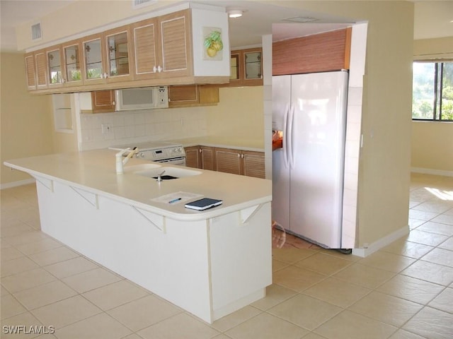 kitchen featuring kitchen peninsula, a breakfast bar, white appliances, sink, and light tile patterned floors