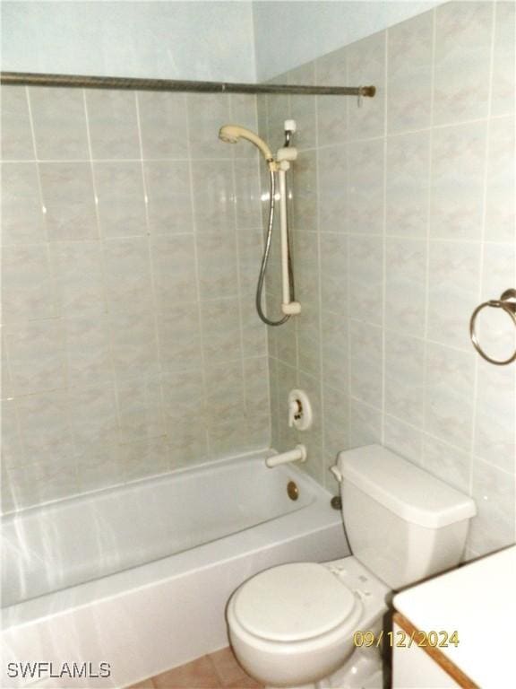 bathroom with tiled shower / bath combo and toilet