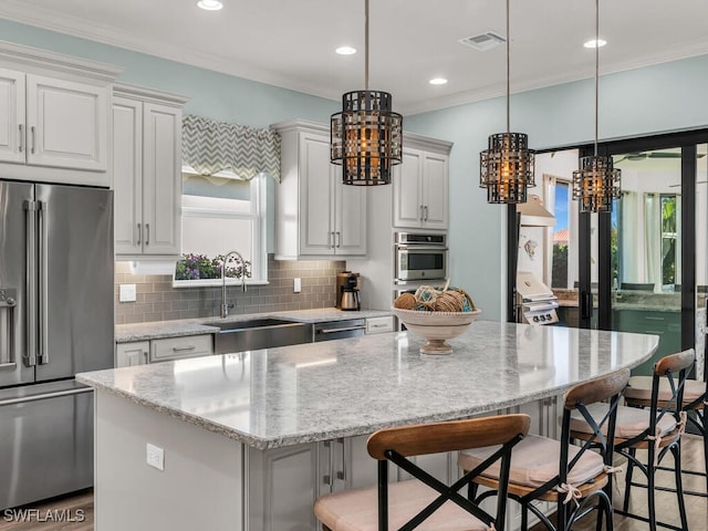 kitchen with crown molding, stainless steel appliances, a sink, and a center island