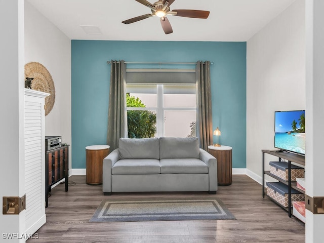 living area with ceiling fan, wood finished floors, and baseboards