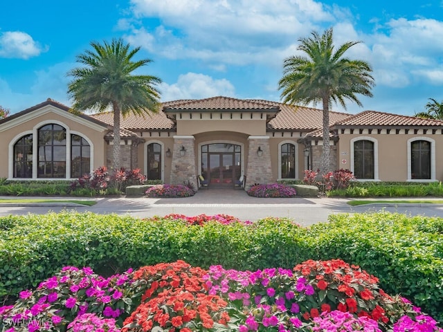 view of front of home with stone siding, a tile roof, and stucco siding