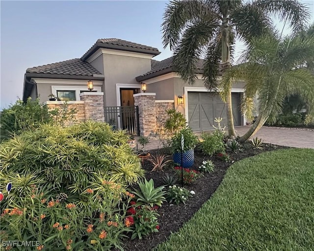 view of front of house featuring a garage, fence, stone siding, decorative driveway, and stucco siding