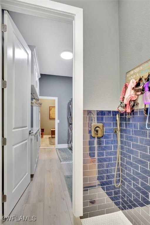 bathroom with hardwood / wood-style flooring and stacked washer / dryer