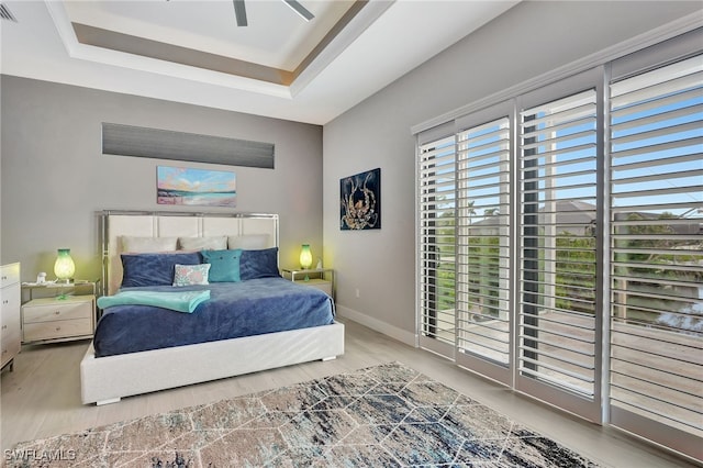 bedroom featuring hardwood / wood-style flooring, ceiling fan, and a tray ceiling