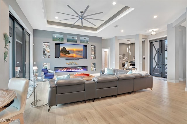 living room featuring a tray ceiling and light hardwood / wood-style flooring