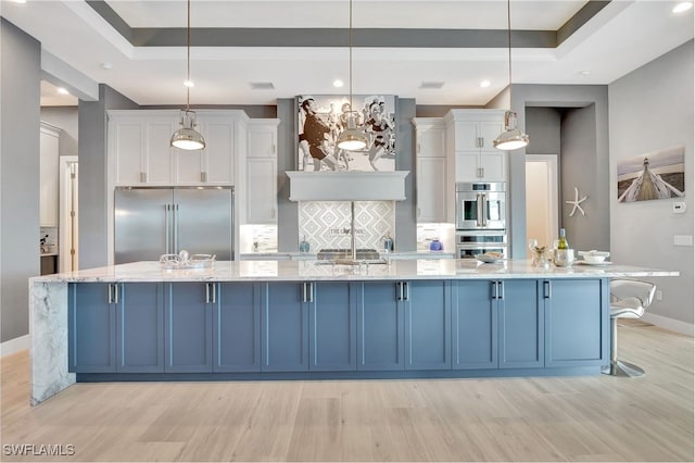 kitchen featuring appliances with stainless steel finishes, hanging light fixtures, and white cabinets