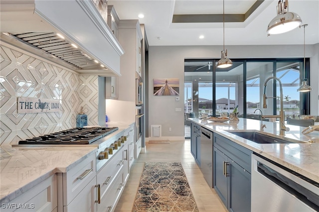 kitchen with premium range hood, decorative light fixtures, a raised ceiling, white cabinetry, and stainless steel appliances