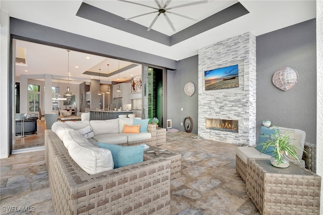 living room with a stone fireplace and a raised ceiling