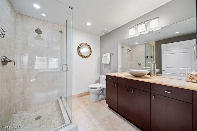 bathroom featuring tile patterned flooring, vanity, toilet, and walk in shower