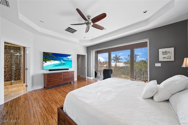 bedroom featuring access to exterior, light wood-type flooring, a raised ceiling, and ceiling fan