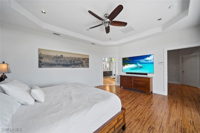 bedroom with a raised ceiling, ceiling fan, and hardwood / wood-style flooring