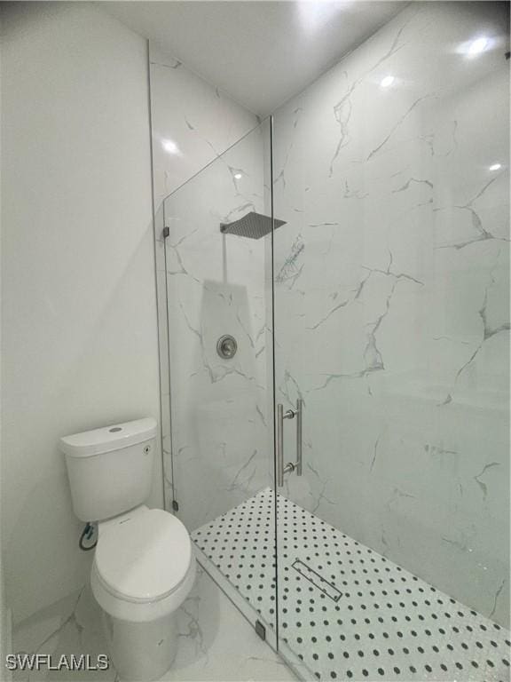 bathroom featuring a shower with shower door and toilet