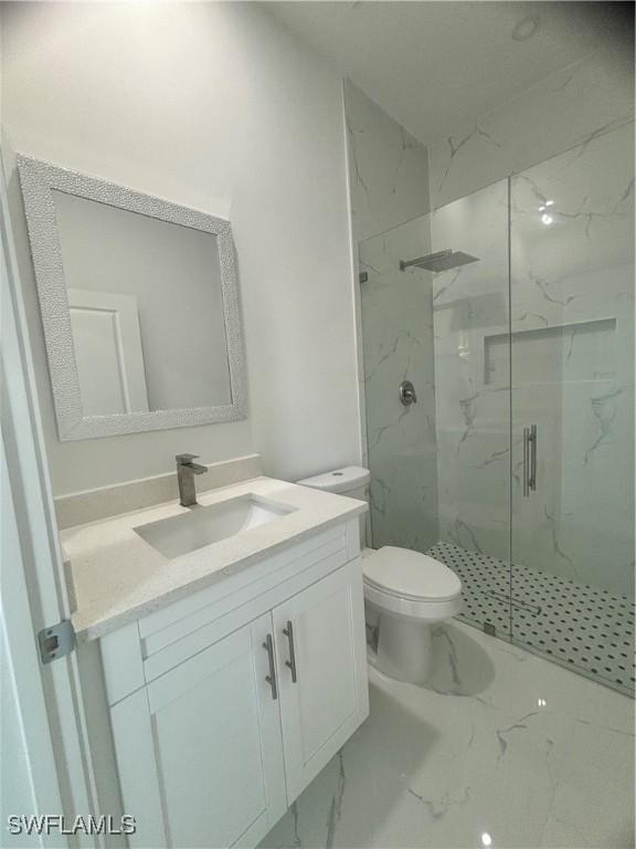 1115 Cumming St E, Lehigh Acres, FL 33974 - bathroom featuring marble look tile flooring, a marble finish shower, and vanity