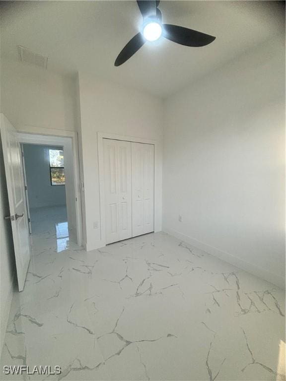 1115 Cumming St E, Lehigh Acres, FL 33974 - unfurnished bedroom featuring a closet, light marble finish flooring, and a ceiling fan