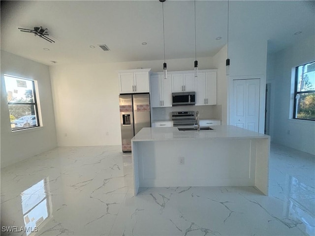 1115 Cumming St E, Lehigh Acres, FL 33974 - kitchen featuring appliances with stainless steel finishes, white cabinetry, a kitchen island with sink, light countertops, and light marble finish floors
