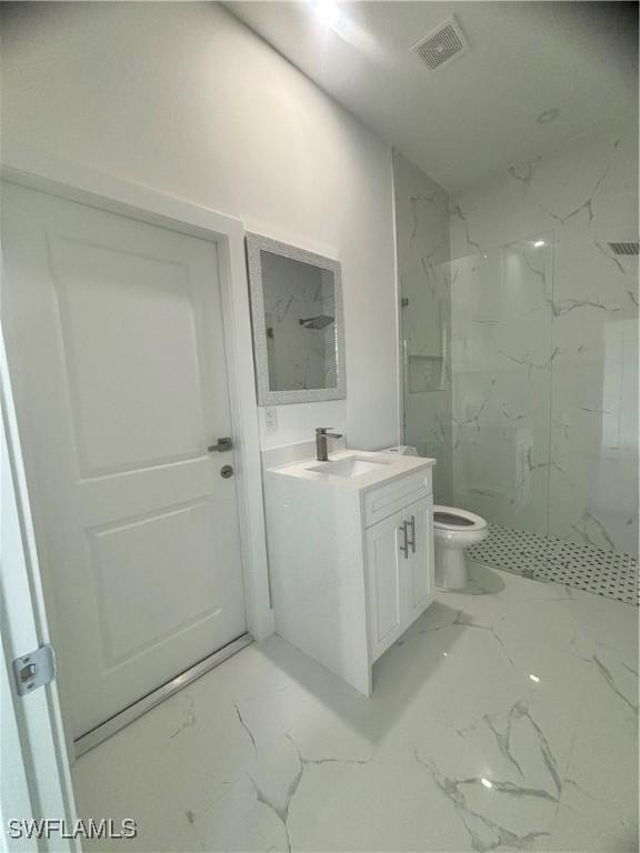 bathroom featuring vanity, toilet, and tiled shower