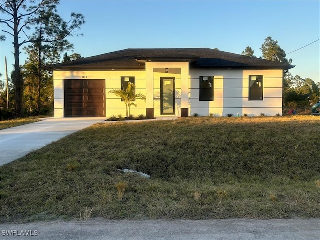 view of front of home featuring a garage, driveway, a front yard, and stucco siding