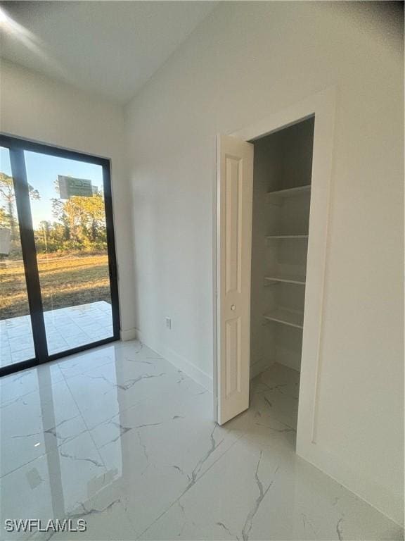 1115 Cumming St E, Lehigh Acres, FL 33974 - unfurnished bedroom with light marble finish floors, access to exterior, and a spacious closet