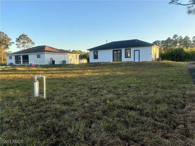 1115 Cumming St E, Lehigh Acres, FL 33974 - rear view of property featuring stucco siding and a yard