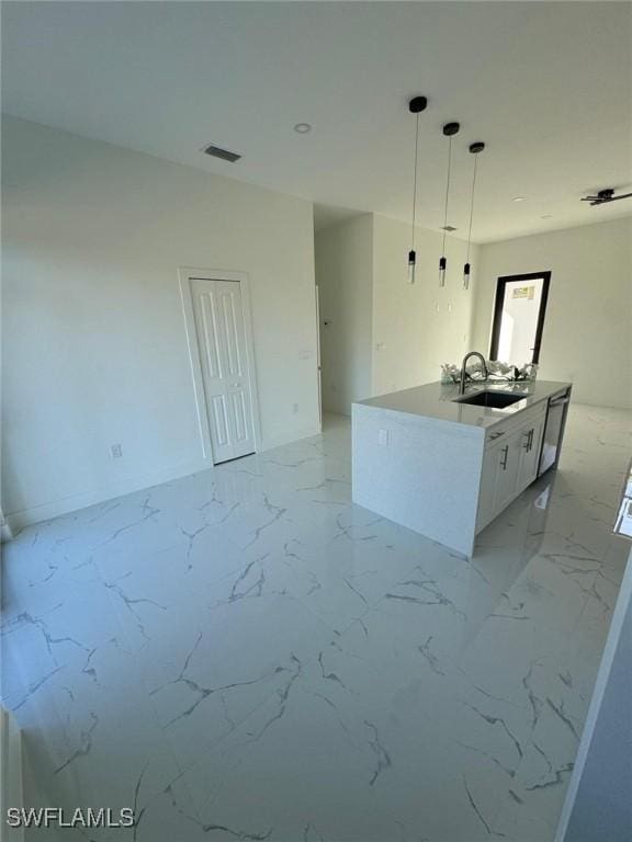 kitchen featuring an island with sink, sink, pendant lighting, and white cabinets