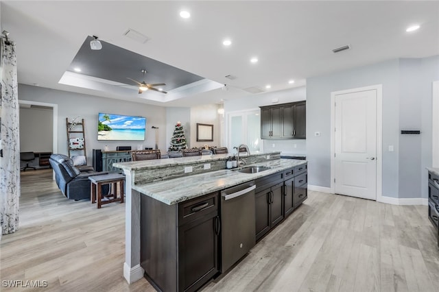 kitchen featuring dishwasher, sink, a kitchen island with sink, a tray ceiling, and dark brown cabinets